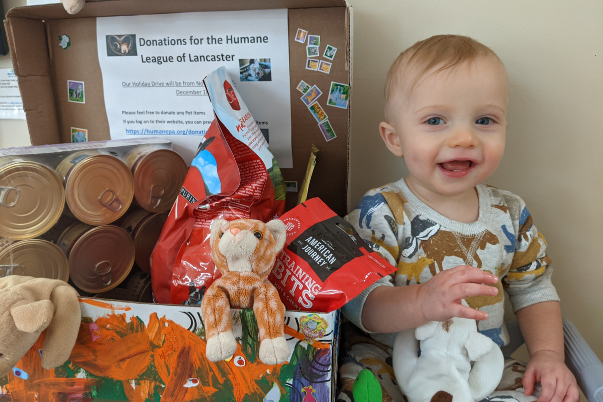 Baby at daycare with box of donations for pets